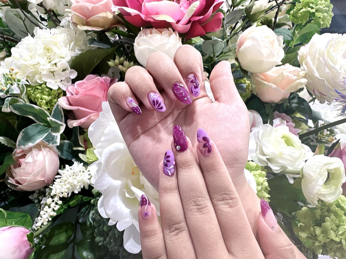 Purple almond nails with floral and butterfly nail art at Blossom's Nails Boutique
